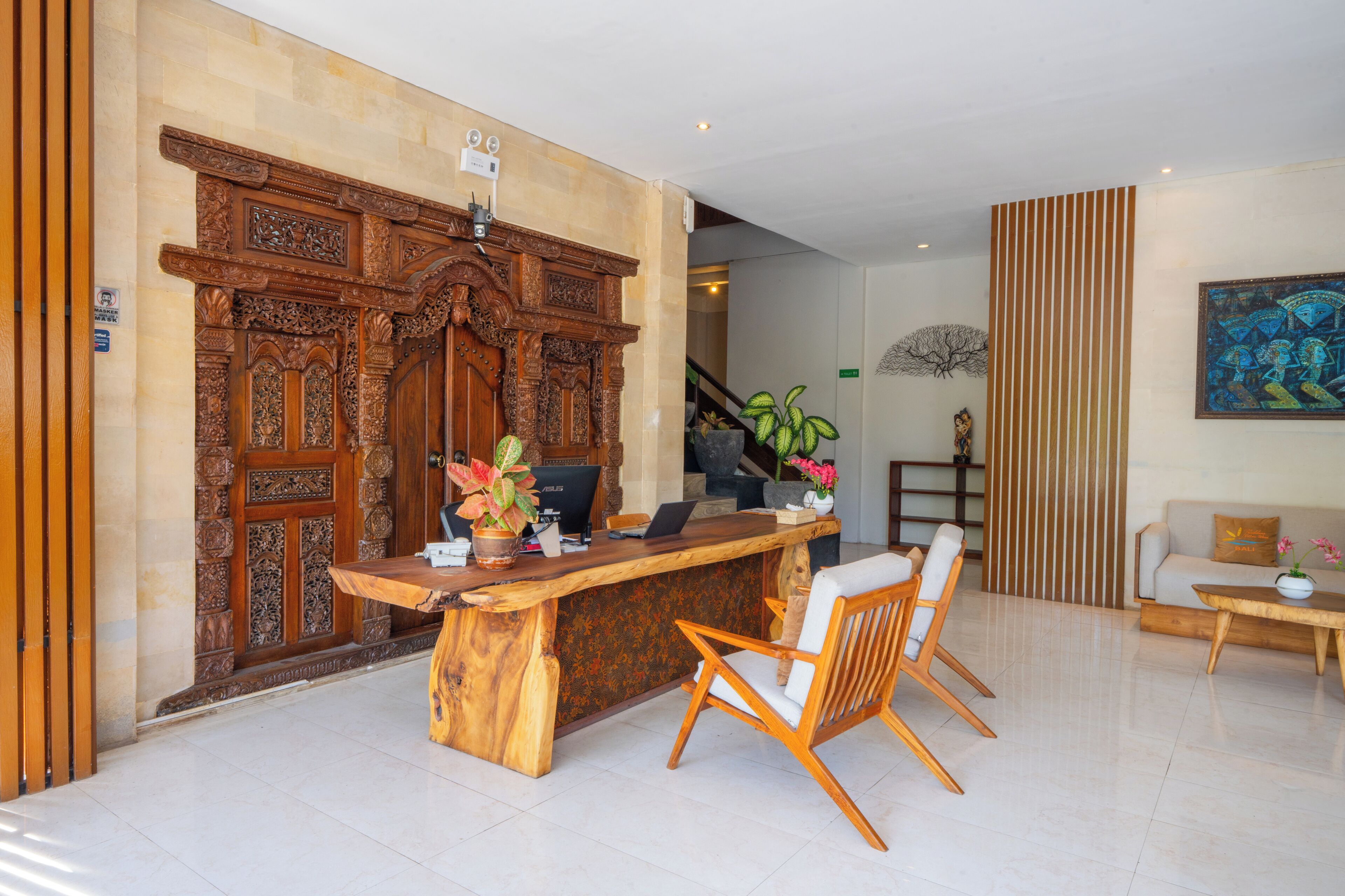 Zona de recepción con un mostrador de madera, una silla, un sofá y una escalera al fondo.