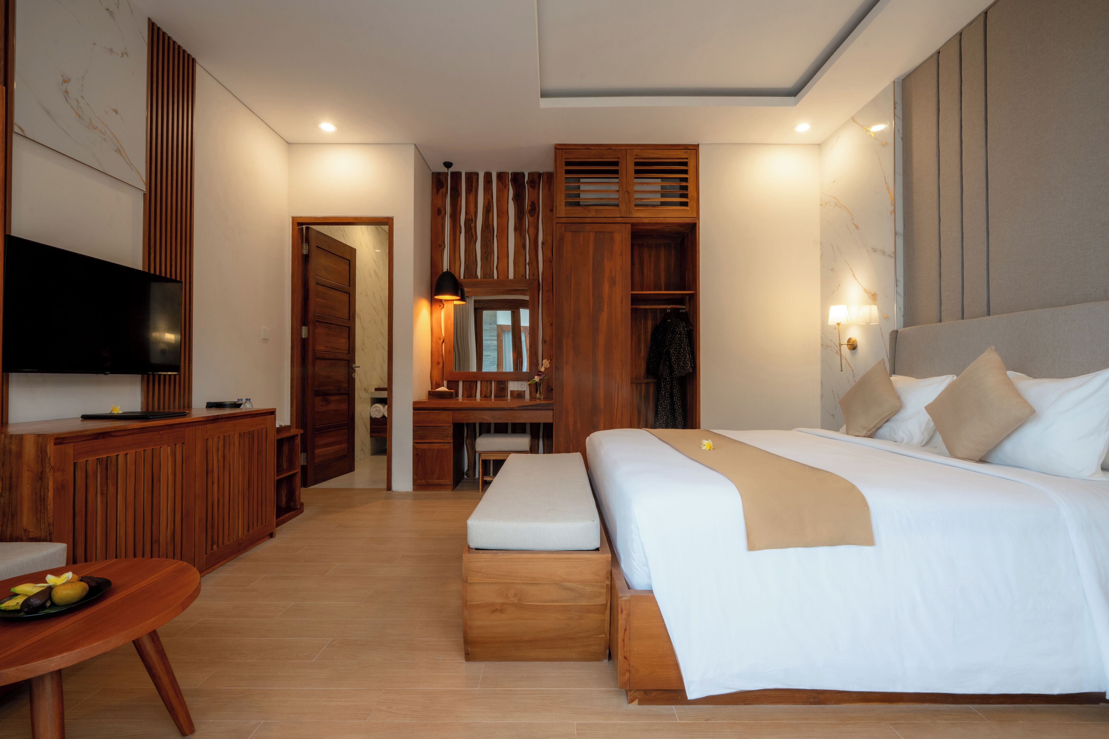 A modern hotel room with a large bed, a desk, a television, and a wardrobe.