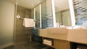 A modern bathroom with a glass-enclosed shower, a large mirror, and a vanity with a sink and towel storage.