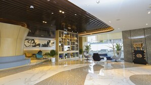 A modern lobby with a marble floor, a large abstract painting, a bookshelf, and seating areas. - Holiday Inn Express Linyi Riverside by IHG (Linyi)