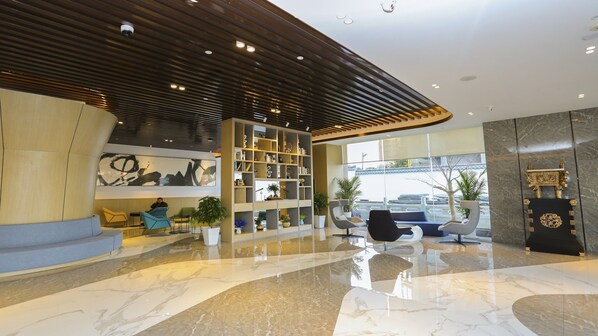 A modern lobby with a marble floor, a large abstract painting, a bookshelf, and seating areas.