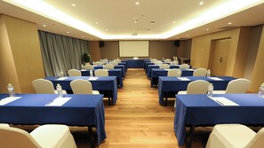 Uma sala de conferências com mesas, cadeiras e uma tela de projeção.
