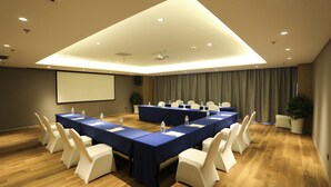 A conference room with a long table, chairs, a projector screen, and a large window with curtains. - Holiday Inn Express Linyi Riverside by IHG (Linyi)