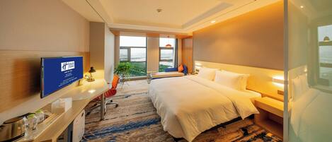 Habitación de hotel con una cama, un escritorio con ordenador, televisor y un amplio ventanal con vistas.