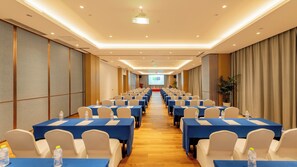 A conference room with rows of tables and chairs, a podium, and a screen at the front. - Holiday Inn Express Linyi Riverside by IHG (Linyi)