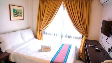 A hotel room with a bed, a desk with a telephone, and a television.