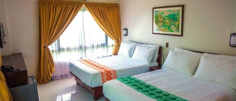 A hotel room with two beds, a desk, and a window with curtains.