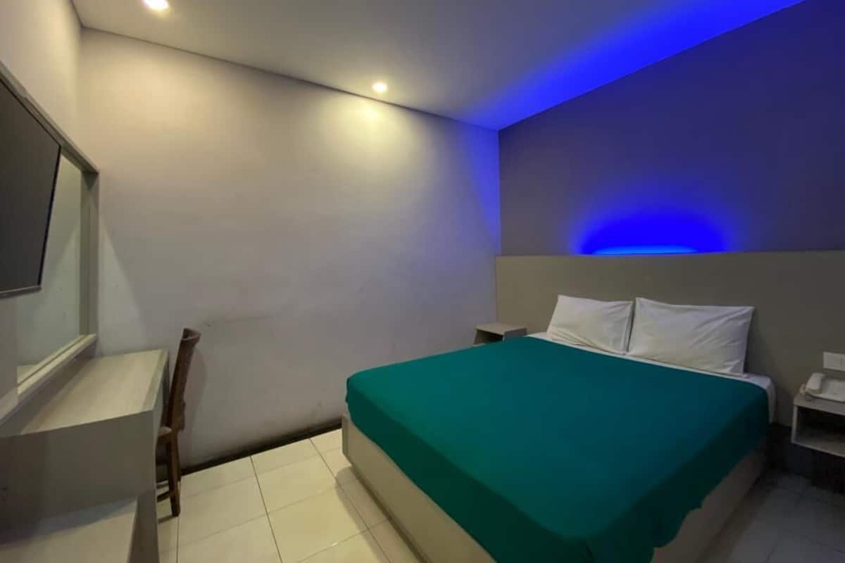 A modern bedroom with a bed, bedside table, and a desk with a chair.
