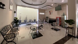 A modern hotel lobby with a central seating area, a flat-screen TV mounted on the wall, and a reception desk. - Hotel Kharisma (Madiun)