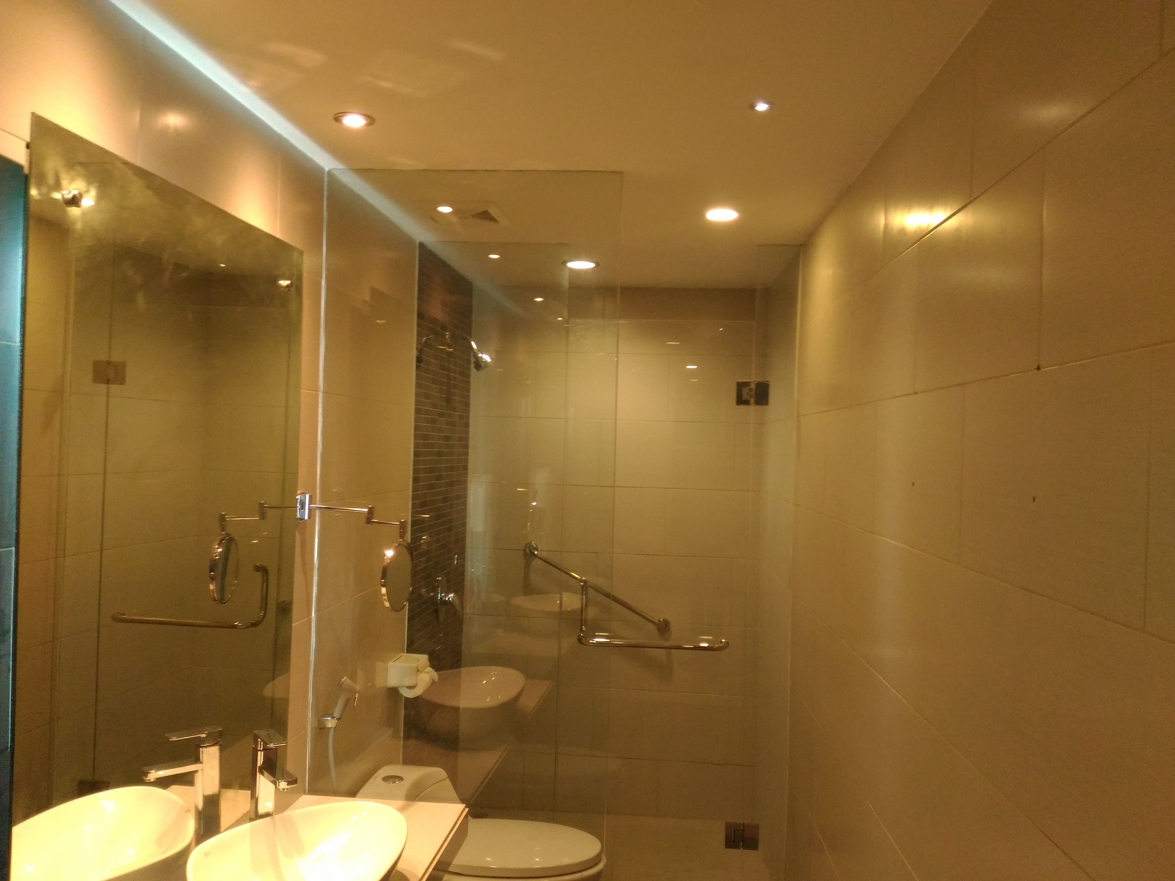 A modern bathroom with a glass shower enclosure, a toilet, and two sinks.