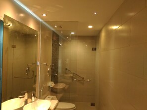 Un baño moderno con cabina de ducha de vidrio, inodoro y dos lavamanos.