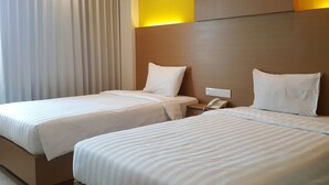 A hotel room with two beds, a bedside telephone, and a window with curtains. - Hotel Kharisma (Madiun)