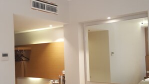 A hotel room with a wooden desk, a chair, a mirror, a radiator, and a small trash bin. - Hotel Kharisma (Madiun)
