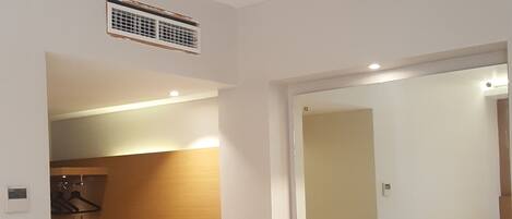 A hotel room with a wooden desk, a chair, a mirror, a radiator, and a small trash bin.