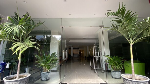 A modern lobby with glass doors, potted plants, and a clean, tiled floor. - Hotel Kharisma (Madiun)