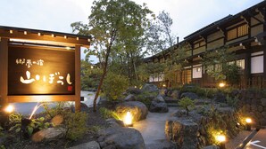A traditional Japanese garden with a wooden sign, large rocks, and stone pathways. - Yamaboushi (Takayama)