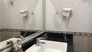 A bathroom with a large mirror, a white sink, and two hair dryers mounted on the wall.