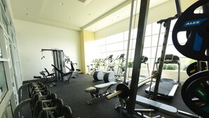 Una palestra con diverse attrezzature per l'allenamento, tra cui tapis roulant, macchinari per pesi e pesi liberi.