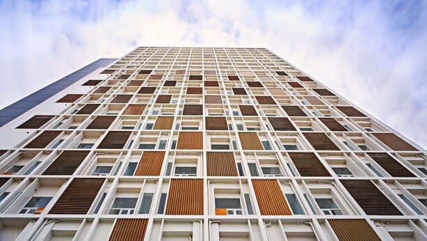 Un edificio alto con una facciata a griglia, numerosi balconi e una varietà di stili di finestra.
