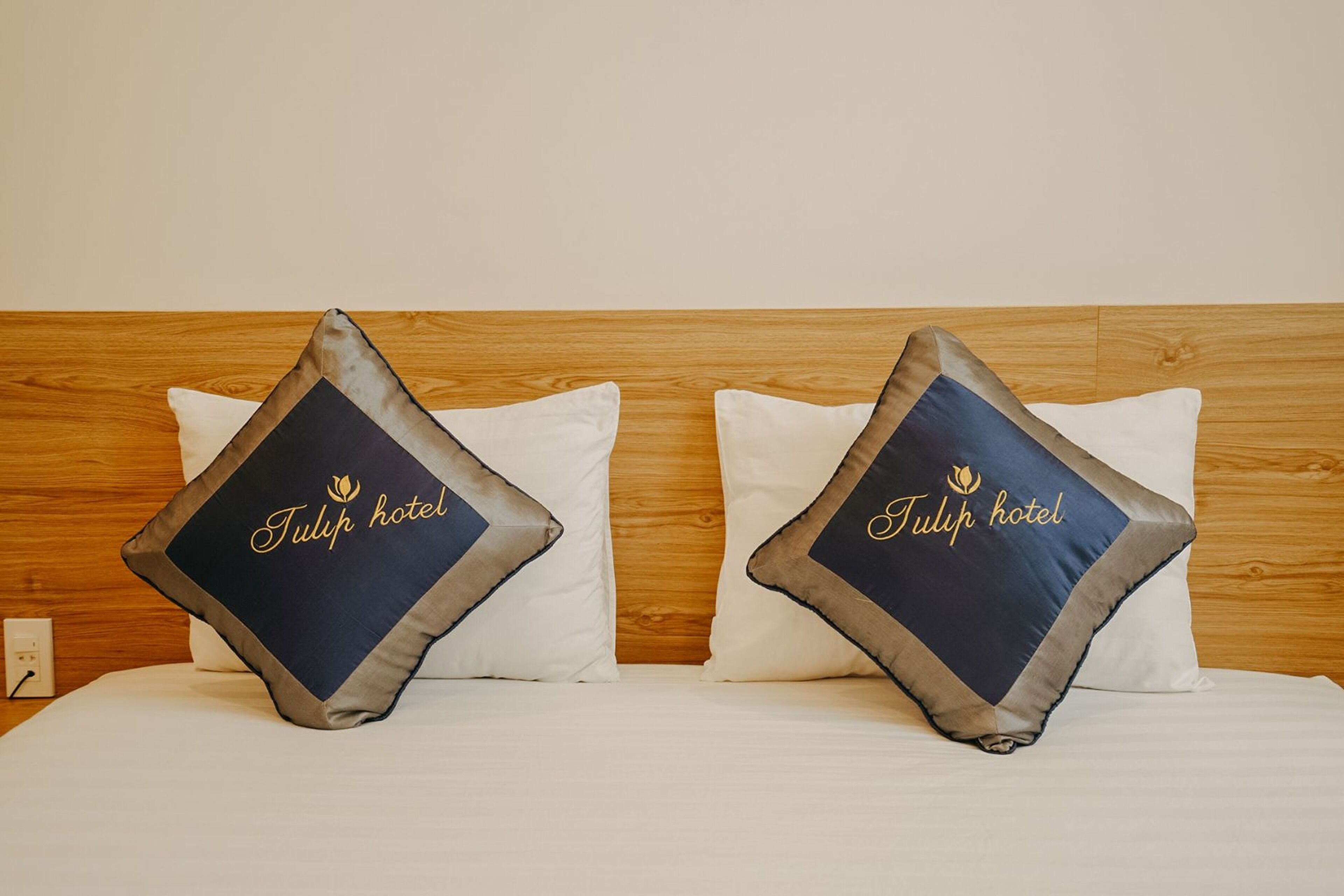 Ett hotellrum med två kuddar i sängen, där hotellets namn är broderat på varje kuddöverdrag.