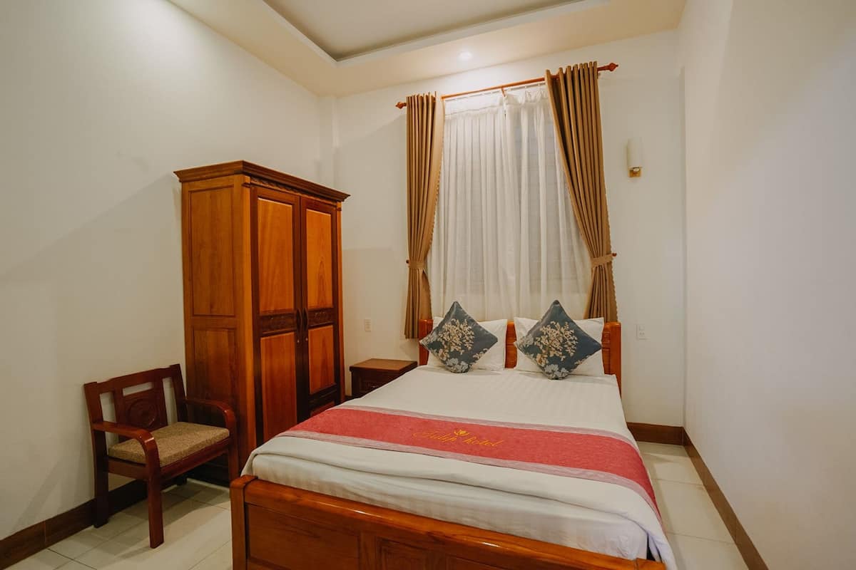 A neatly arranged bedroom with a wooden bed, a wooden wardrobe, and a chair.