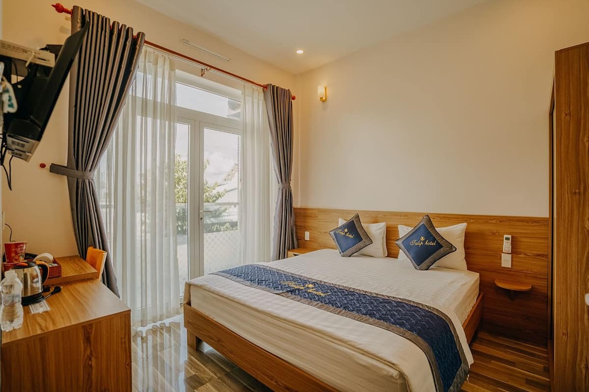 A hotel room with a bed, a desk, and a window with curtains.