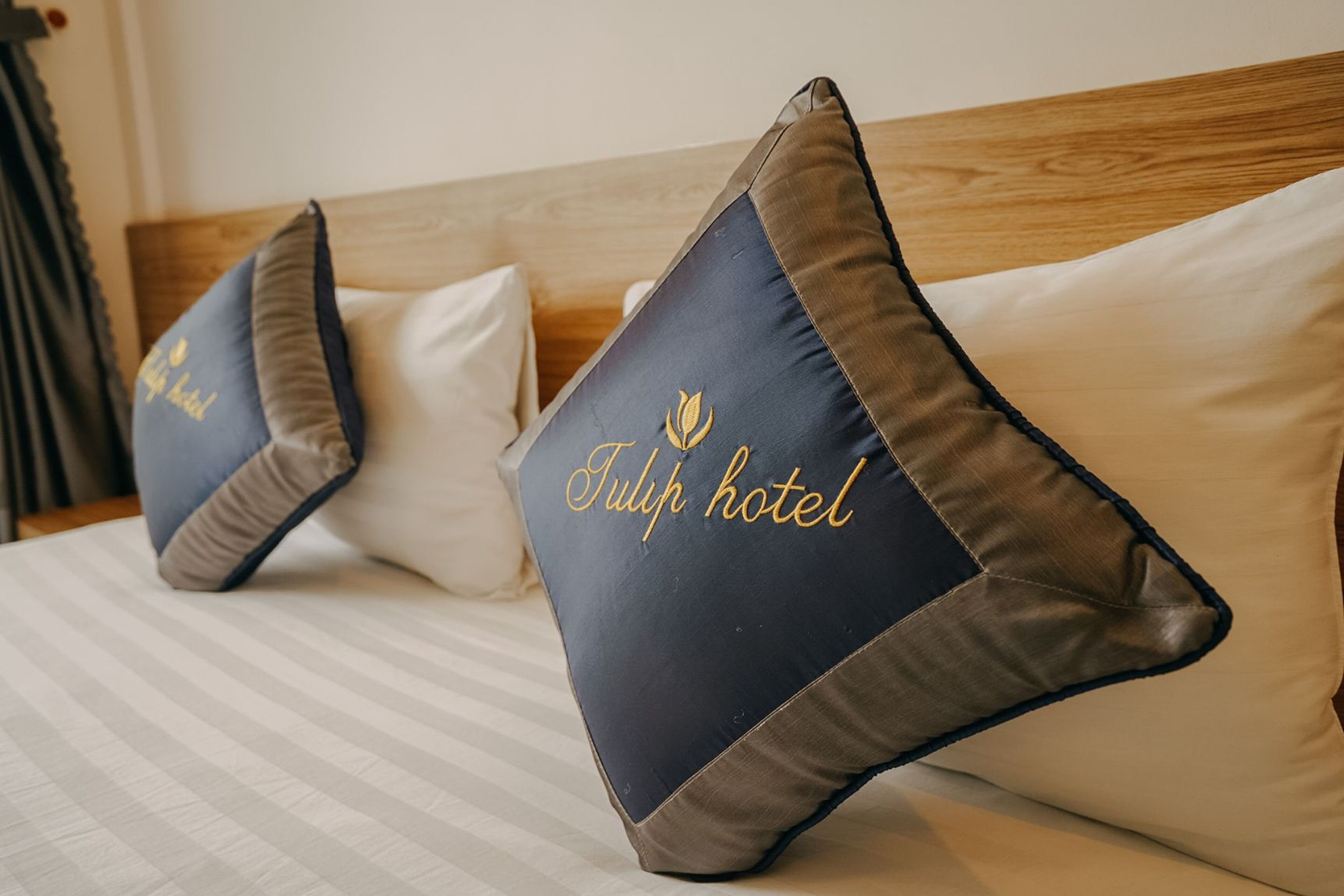 En seng med stribet sengetøj og to puder med teksten "Tulip hotel".