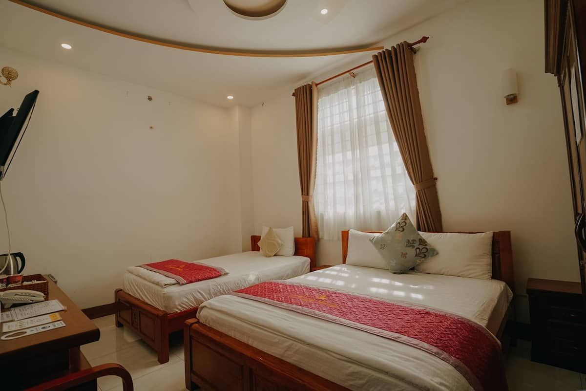 A hotel room with two beds, a desk with a telephone, and a lamp.