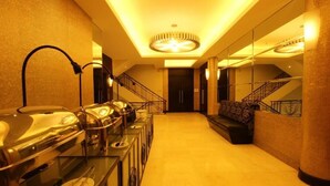 Een hotel lobby met een buffetgedeelte, een trap en een zithoek.