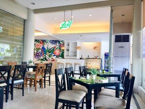 Un restaurant au décor moderne, avec une salle à manger comprenant des tables et des chaises, une cuisine à l’arrière-plan et une enseigne « Leaf » au-dessus de l’entrée.