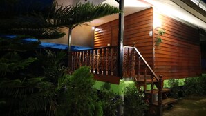 Una casa de madera con porche, escaleras y un pequeño jardín con plantas.