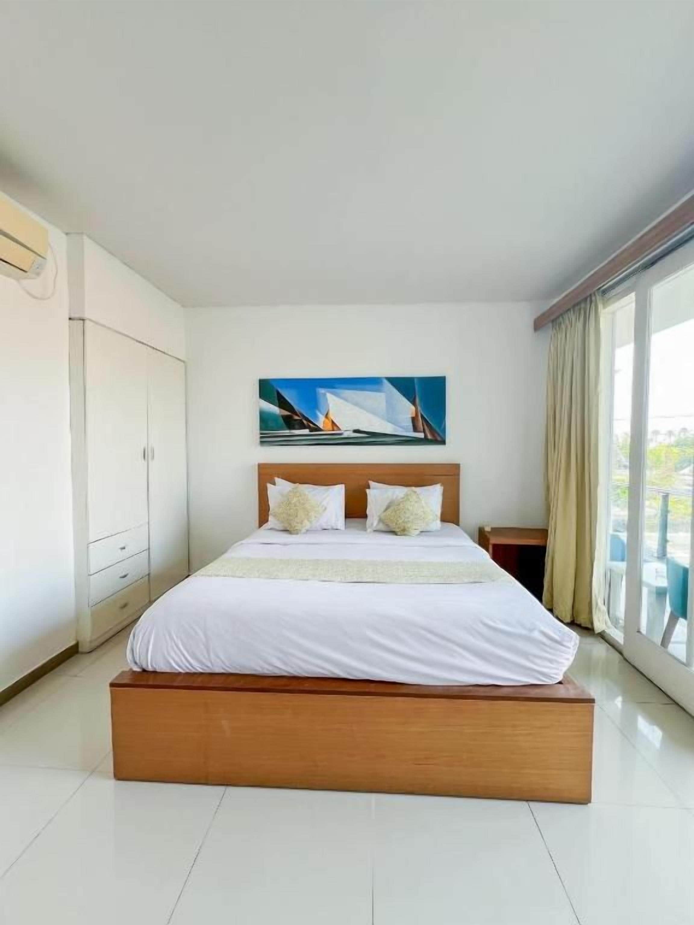 Habitación de hotel con una cama grande, un cuadro en la pared y vistas por la ventana.