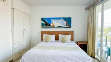 Habitación de hotel con una cama grande, un cuadro en la pared y vistas por la ventana.