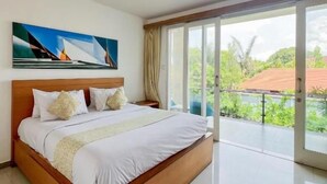 A modern bedroom with a large bed, a painting on the wall, and a view of greenery through the window. - Apple Suite Apartment (Keroboken Kelod)