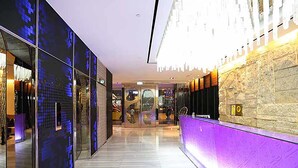 A modern hotel lobby with a glass partition, a reception desk, and a stone wall. - Royal Group Hotel Chang Chien Branch (Kaohsiung)