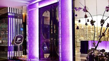 A hotel entrance with a modern design, including a glass door and a decorative wall with a pattern.