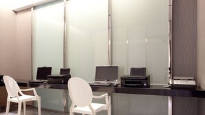A modern office space with a glass partition, two white chairs, and a desk with multiple computers and printers. - Royal Group Hotel Chang Chien Branch (Kaohsiung)