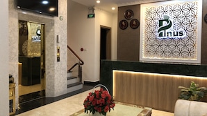 Un'hall dell'hotel con una reception, una scala e una parete decorata con un orologio e una targa.