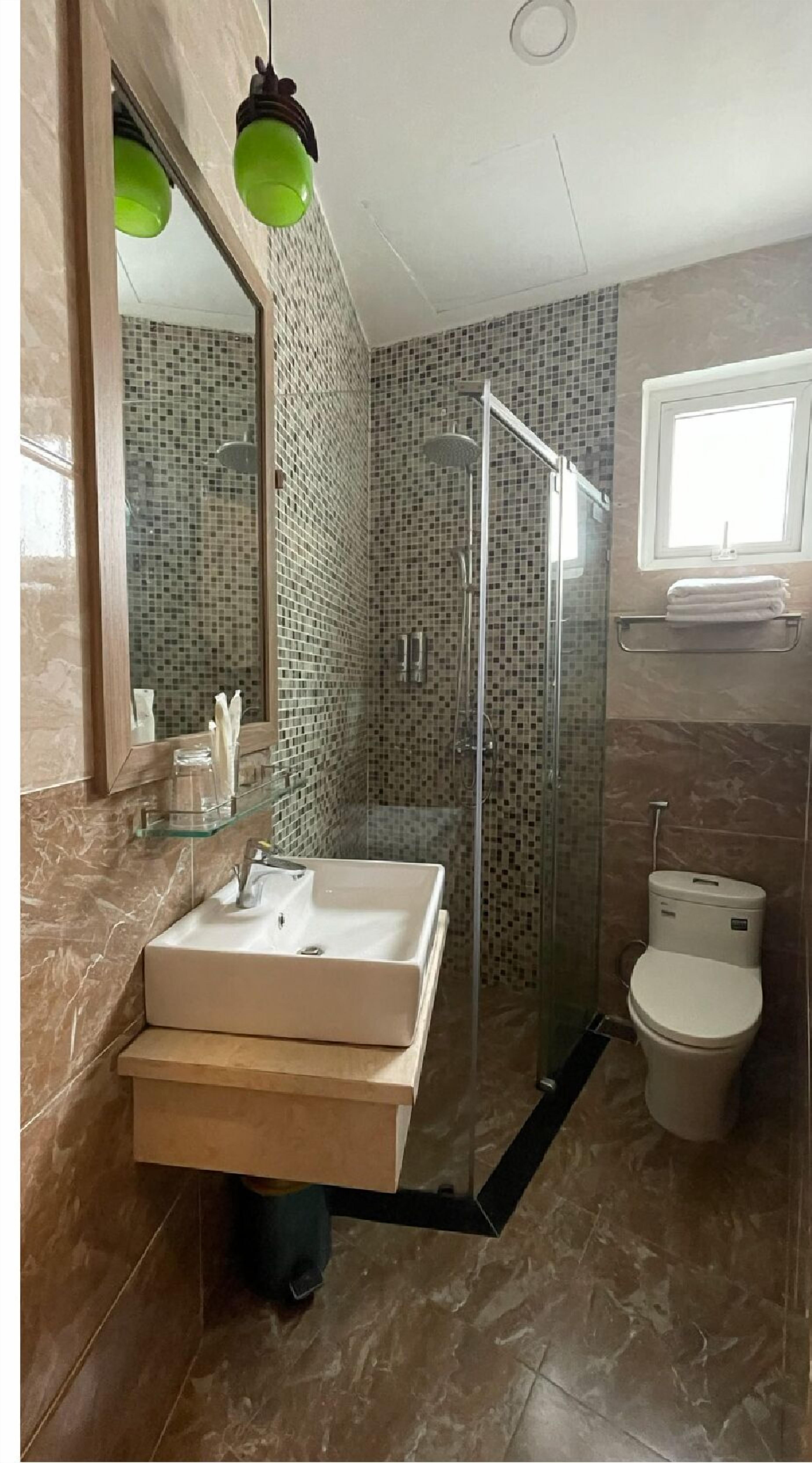 Ein modernes Badezimmer mit einer Duschkabine, einem weißen Waschbecken und einer Toilette.