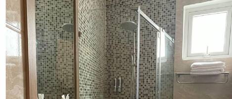 Ein modernes Badezimmer mit einer Duschkabine, einem weißen Waschbecken und einer Toilette.