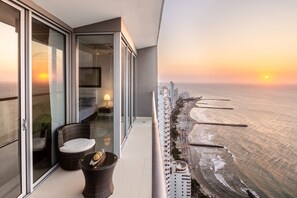 A balcony with a view of the ocean and cityscape at sunset.