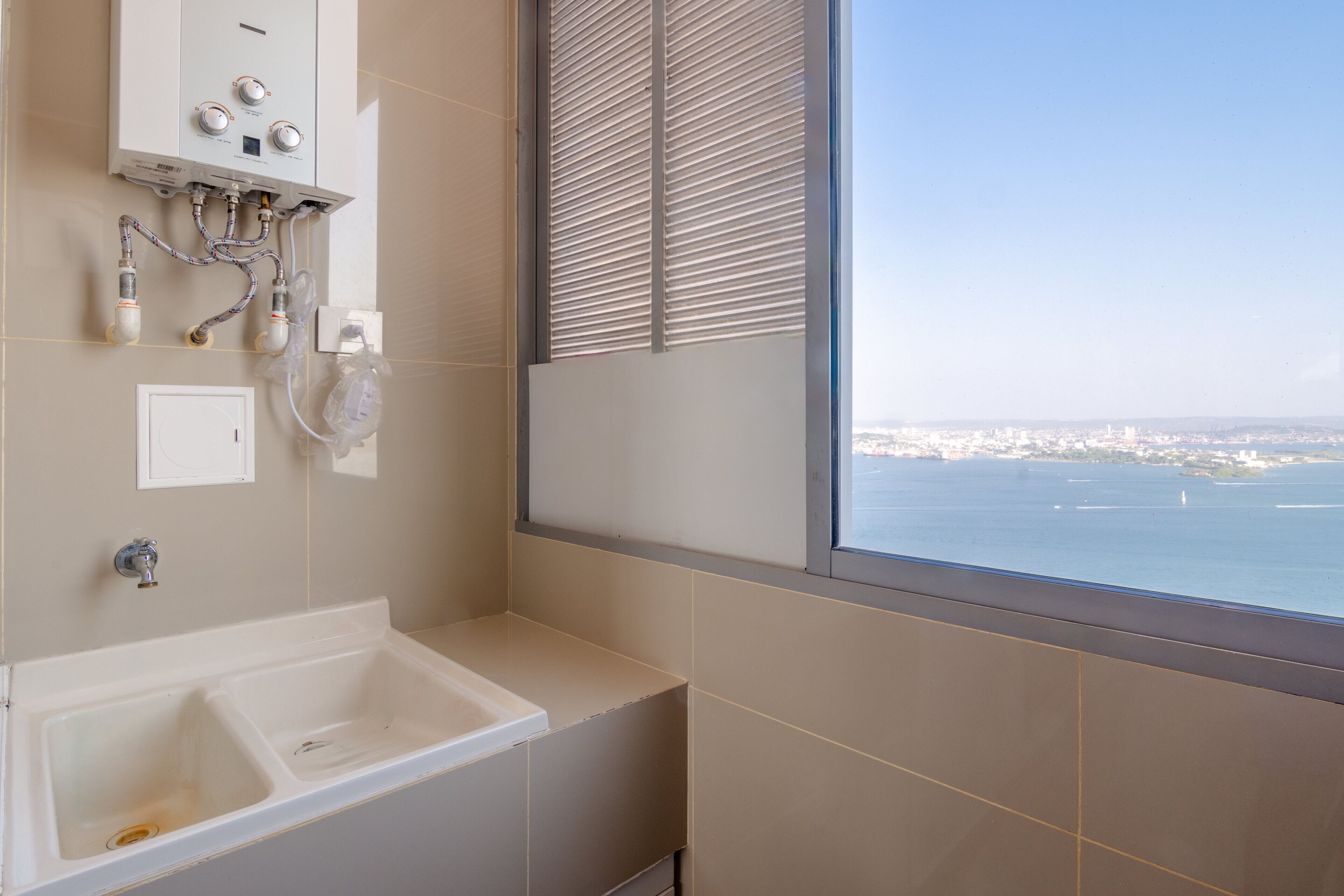 A bathroom with a large window, a bathtub, and a visible water heater.