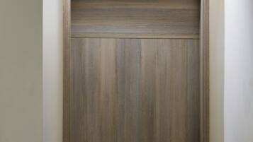 A wooden door with a keypad lock, a number plate above it, and a doormat at the base.