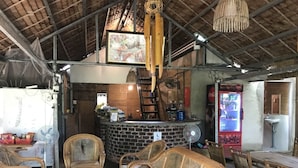 Interior rústico com móveis de vime, balcão de tijolos e geladeira Coca-Cola.