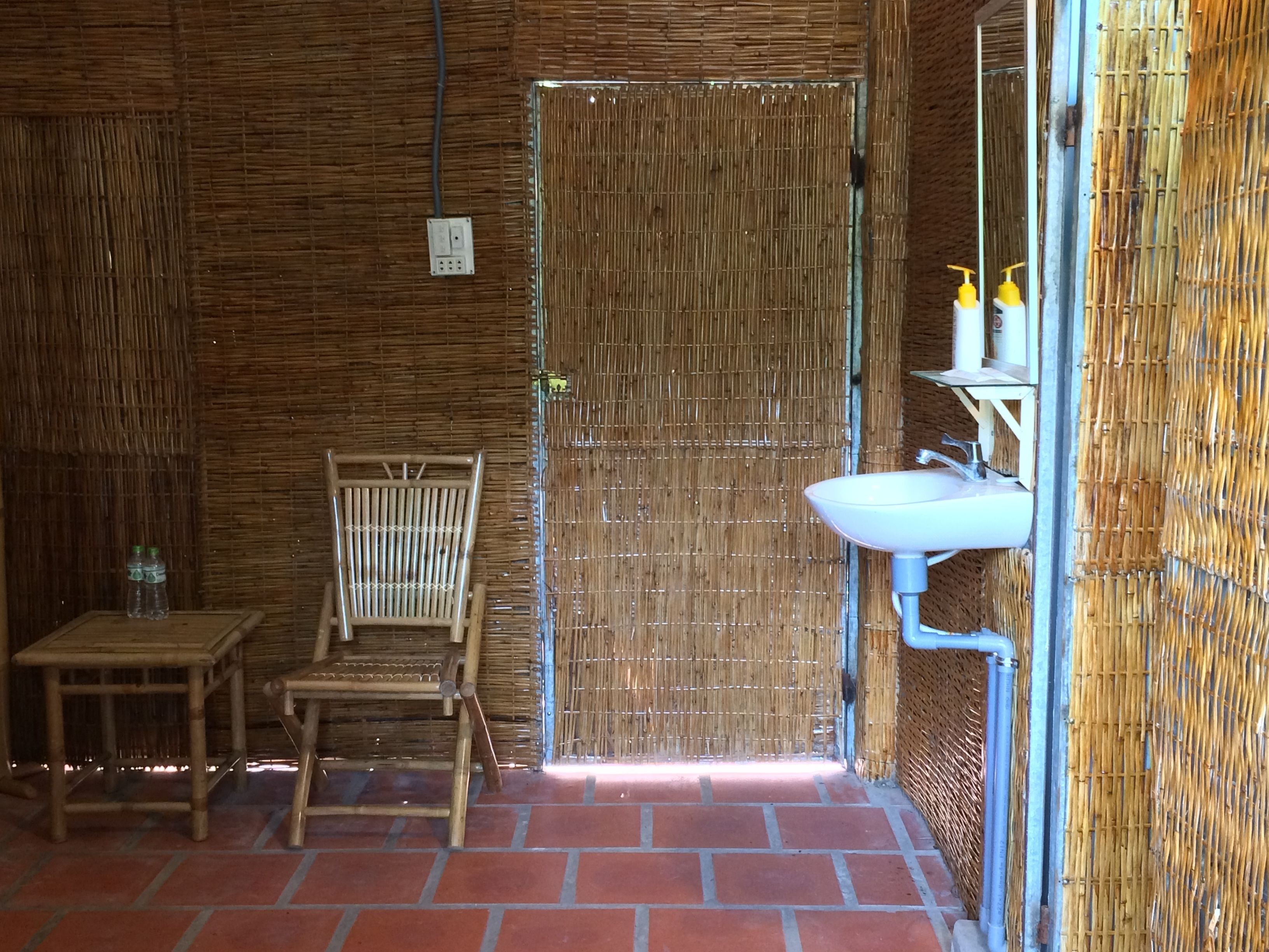 A bathroom with a bamboo wall, a white sink, and a chair.