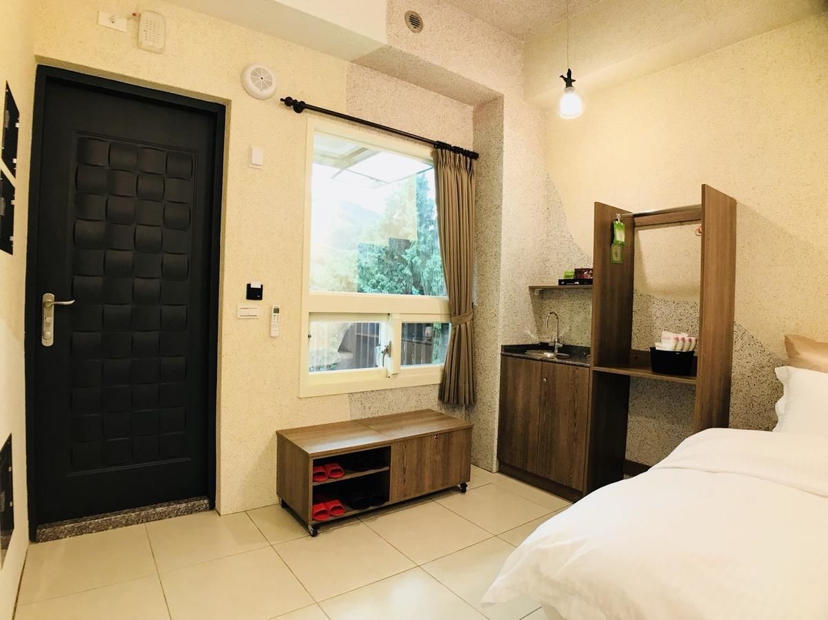 Un dormitorio con una cama, una ventana con cortinas, un armario de madera y una puerta negra.