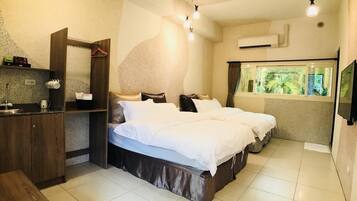 Habitación de hotel con cama, escritorio, espejo y ventana con vista a la vegetación.