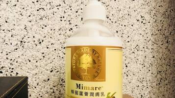 A bottle of Mimare lotion on a wooden surface against a speckled wall.
