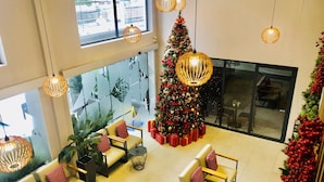 Un vestíbulo amplio con techos altos, mobiliario moderno y un gran árbol de Navidad.