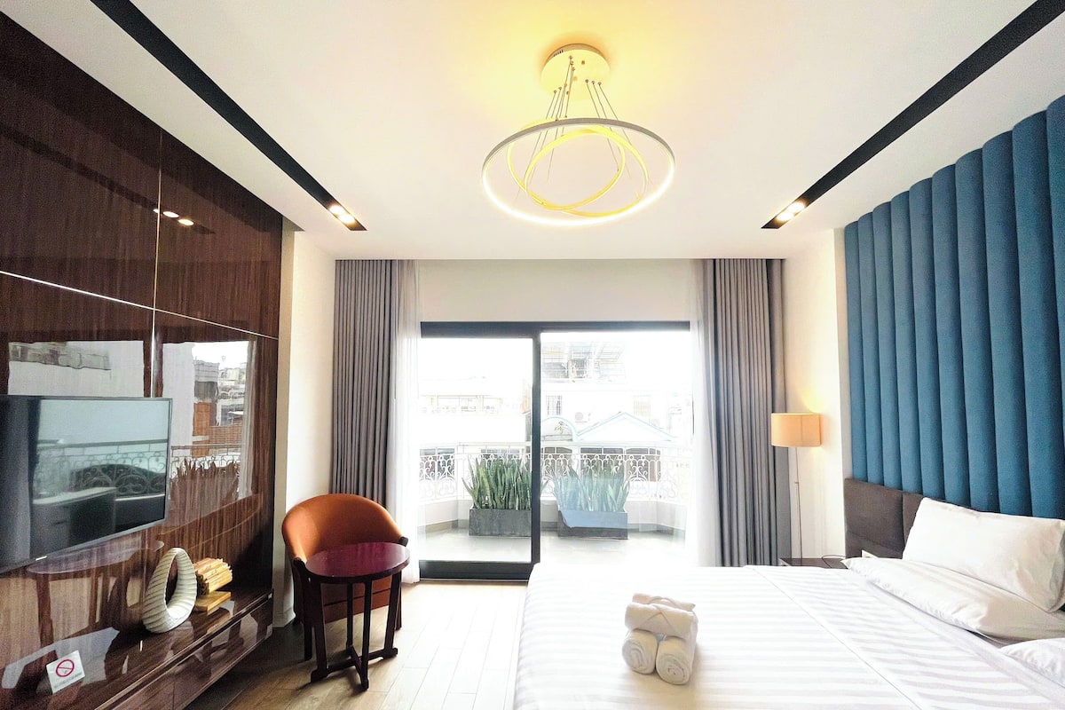 A hotel room with a bed, a TV, a seating area, and a view of the outside.